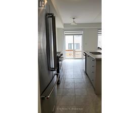 A kitchen with a refrigerator and a view of a balcony.