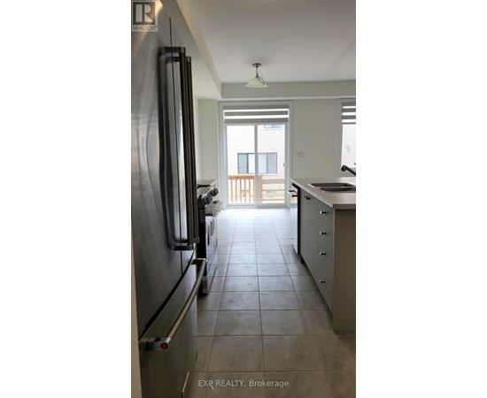 A kitchen with a refrigerator and a view of a balcony.