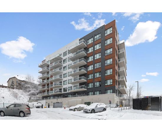 A large apartment building with a parking lot in front of it.