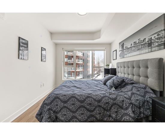 A bedroom with a large bed and a window overlooking a building.