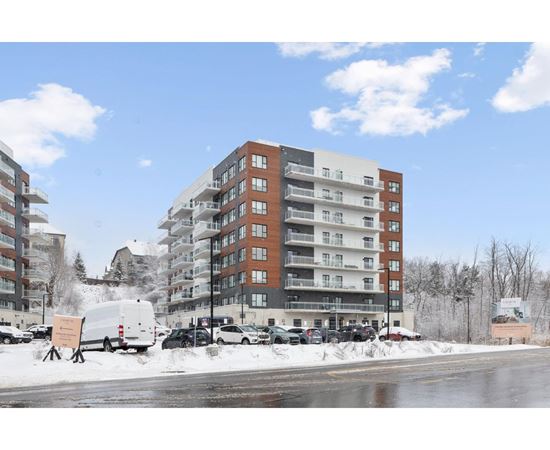 A large apartment building with a parking lot in front of it.