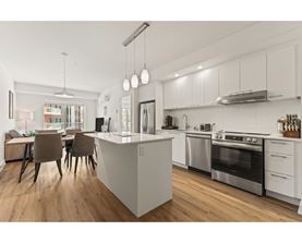 A modern kitchen with a white island and stainless steel appliances.