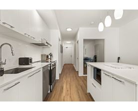 A modern kitchen with white cabinets and a wooden floor.