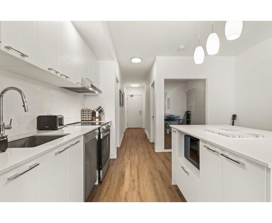 A modern kitchen with white cabinets and a wooden floor.