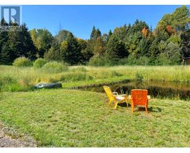 A yellow chair sits next to a brown chair on a lawn.