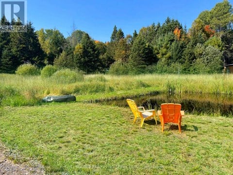 A yellow chair sits next to a brown chair on a lawn.
