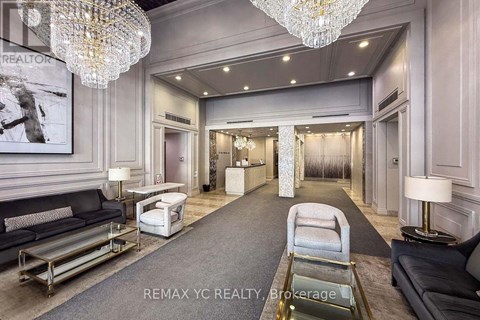 A well-lit, elegant living room with a grey carpet and a chandelier.