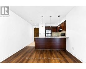 A spacious kitchen with dark wood floors and white walls.
