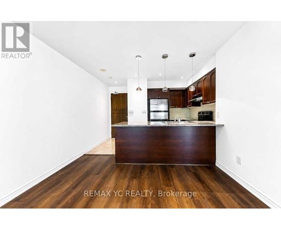 A spacious kitchen with dark wood floors and white walls.