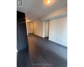 A spacious room with wooden flooring and white walls.