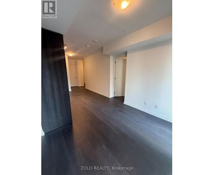 A spacious room with wooden flooring and white walls.