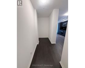 A hallway with white walls and dark wood flooring.