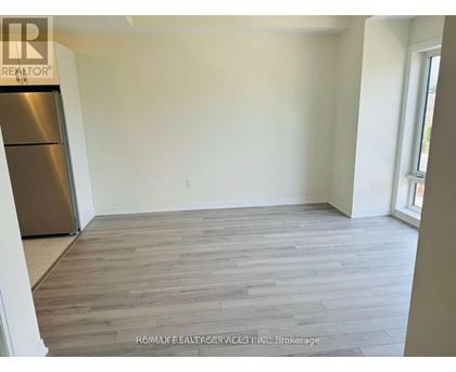 A room with a wooden floor and a refrigerator.