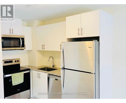 A kitchen with white cabinets and a stainless steel refrigerator.