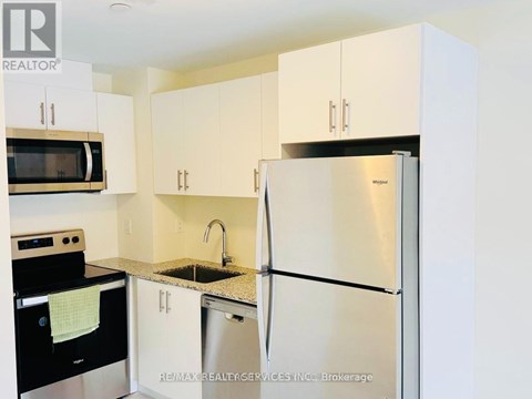 A kitchen with white cabinets and a stainless steel refrigerator.