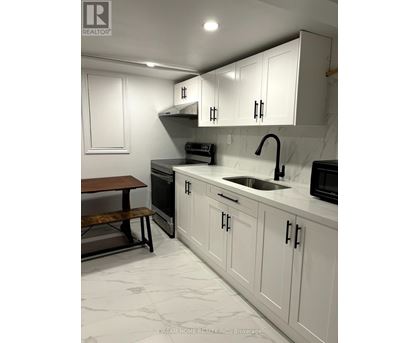 A kitchen with white cabinets and a marble countertop.