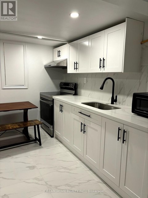 A kitchen with white cabinets and a marble countertop.