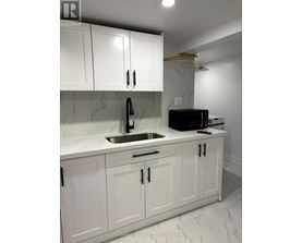 A kitchen with white cabinets and a marble countertop.