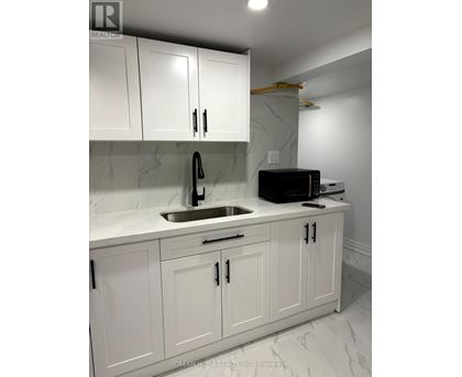 A kitchen with white cabinets and a marble countertop.