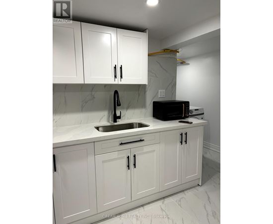 A kitchen with white cabinets and a marble countertop.