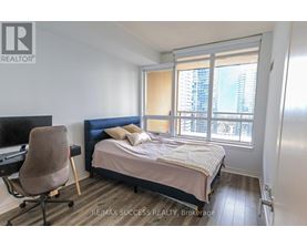 A bedroom with a bed, chair, and window.