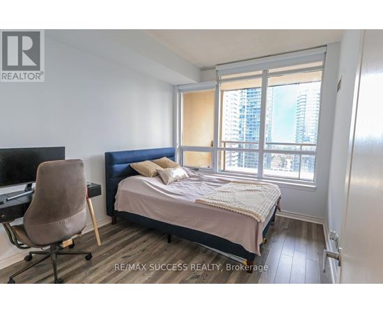 A bedroom with a bed, chair, and window.