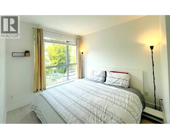 A bedroom with a large bed and a window with curtains.
