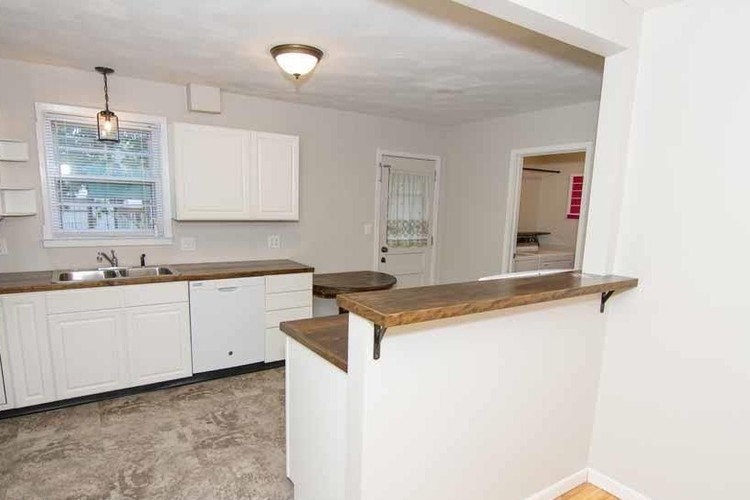 A kitchen with white cabinets and a window above the sink.