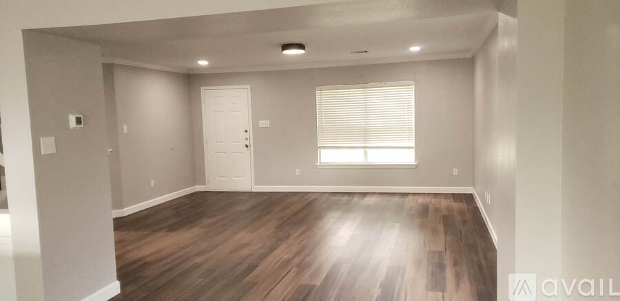 A room with wooden floors and a window with blinds.