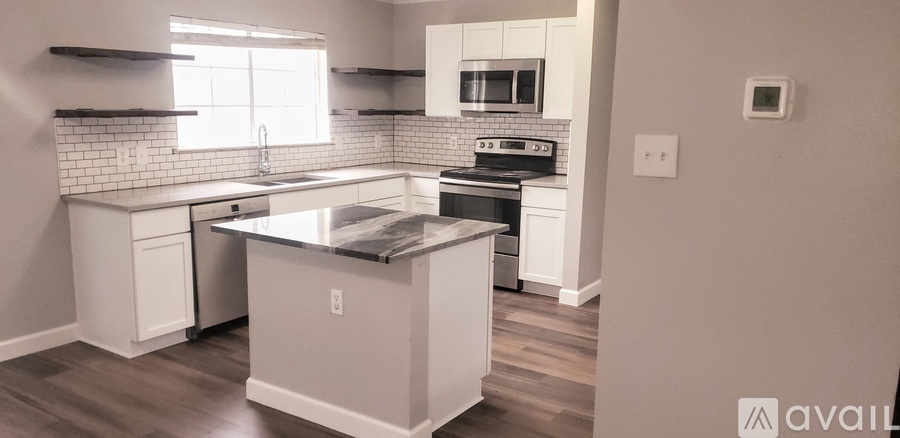 A kitchen with white cabinets and a black counter top.