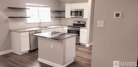A kitchen with white cabinets and a black counter top.