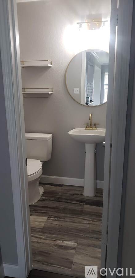 A bathroom with a toilet, sink, and mirror.
