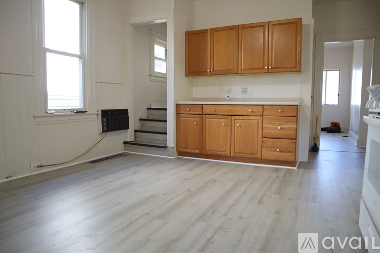 A kitchen area with wooden cabinets and a staircase leading to a lower level.