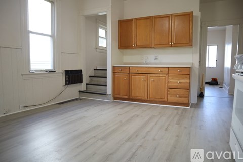 A kitchen area with wooden cabinets and a staircase leading to a lower level.