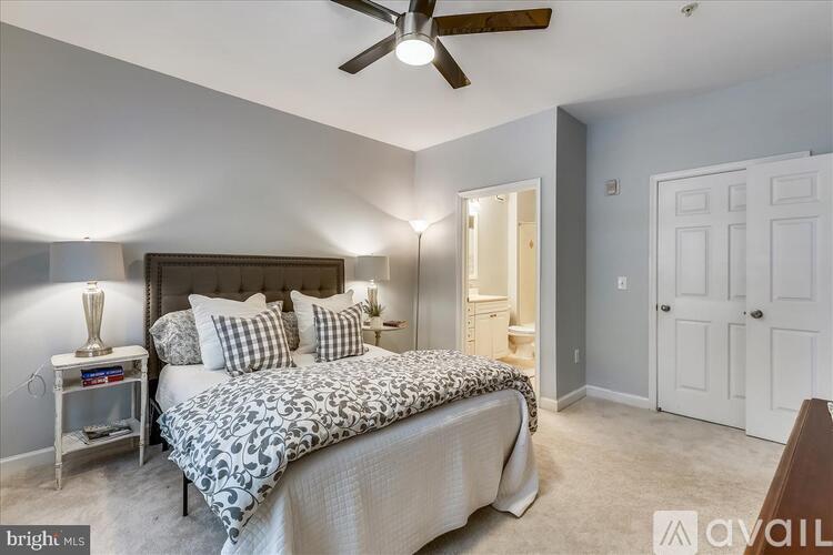 A bedroom with a bed, a ceiling fan, and a nightstand with a lamp.