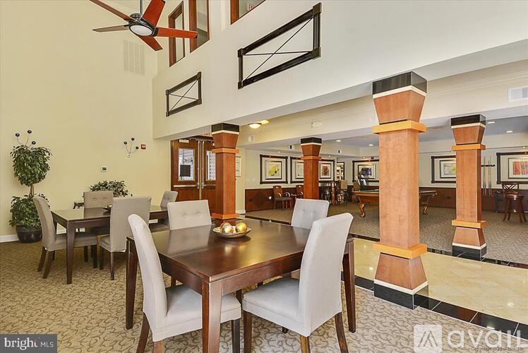 A dining room with a wooden table surrounded by chairs and a ceiling fan.