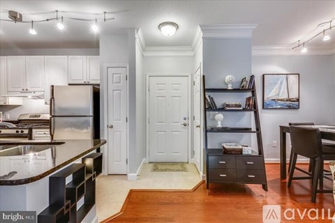 A brightly lit kitchen with white cabinets and a wooden floor.