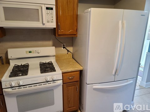 A white fridge stands next to a white stove in a kitchen.