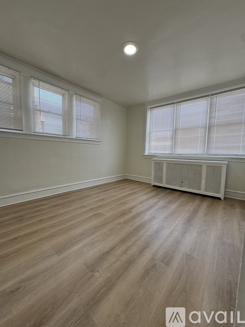 A room with wooden flooring and a window with blinds.