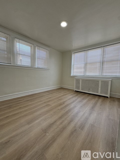 A room with wooden flooring and a window with blinds.