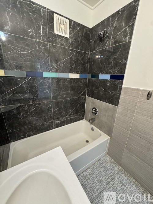 A bathroom with a marble wall and a white bathtub.