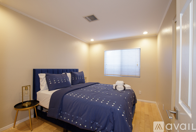 A bedroom with a bed covered in a blue bedspread with white stars on it.