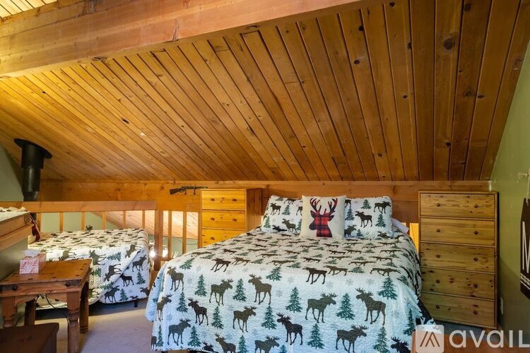 A bedroom with wooden walls and ceiling, two beds with deer patterns, and a wooden dresser.