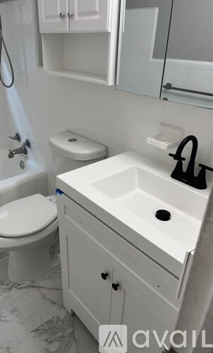 A white bathroom with a toilet, sink, and mirror.