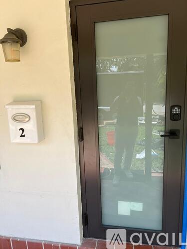 A glass door with a black handle and a sign on the wall that says 2.