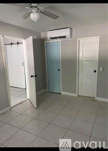 A room with a ceiling fan, two doors, and a wall-mounted air conditioner unit.