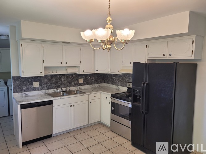A kitchen with white cabinets and a black refrigerator.