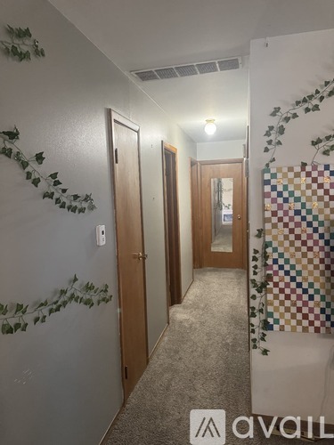 A hallway with a wall decoration of green leaves and a wall hanging.