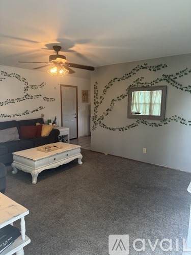 A room with a ceiling fan and a wall decoration.