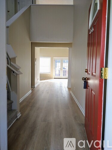 A hallway with a red door and wooden floors.